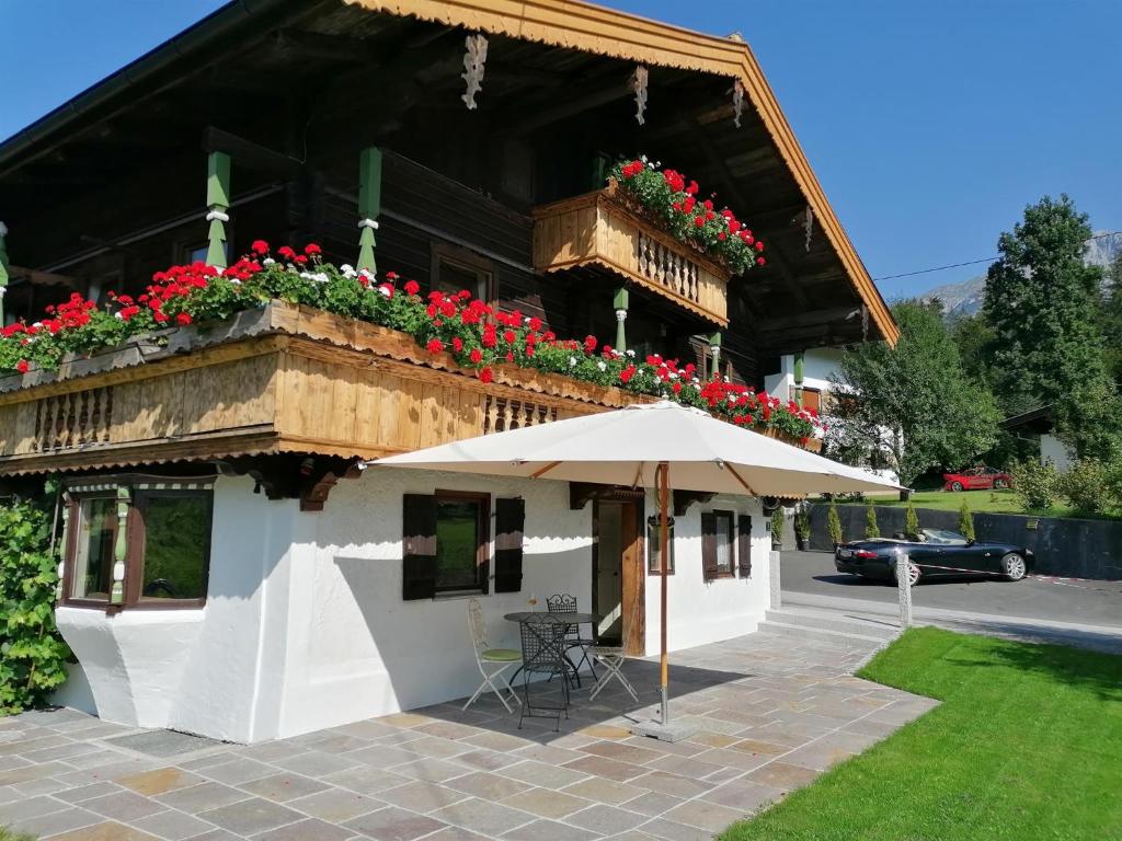 an umbrella in front of a building with flowers at Oberholzer Landhaus & Appartement in Ellmau