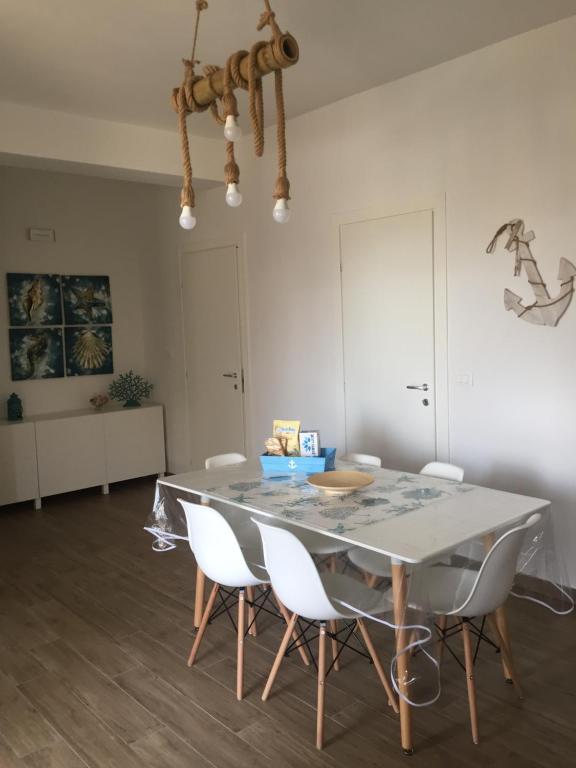 een eetkamer met een tafel en witte stoelen bij LoVi apartments Porto Palo in Porto Palo