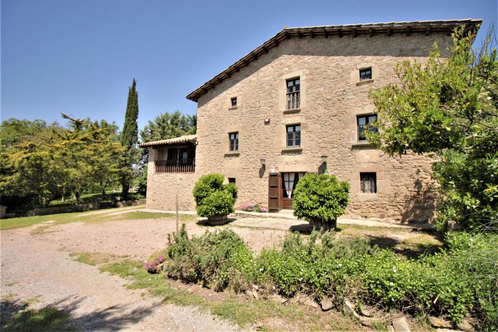 an old stone building with trees and bushes at Cal Terri Rural in Perafita