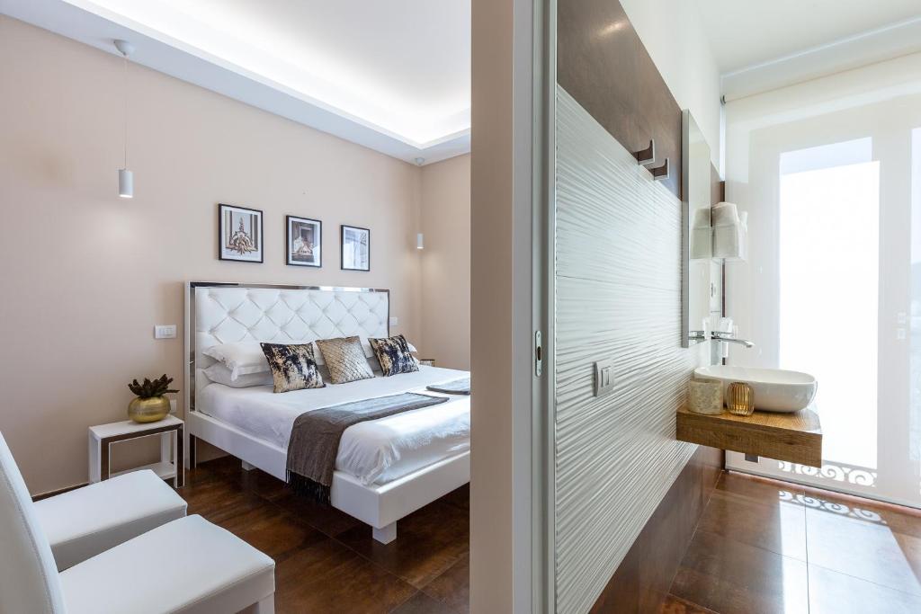 a white bedroom with a bed and a bathroom at Club 57 Imperial Rooms in Cagliari