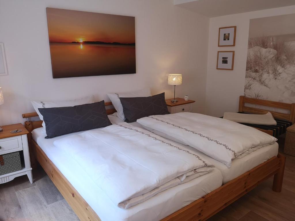 a bedroom with a large white bed with a picture on the wall at Ferienhaus Sommerlust in Ueckeritz