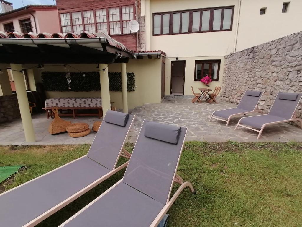 un patio con 2 tumbonas y una sombrilla en EL JARDÍN DE ALEYDA, VV VACACIONAL en Llanes