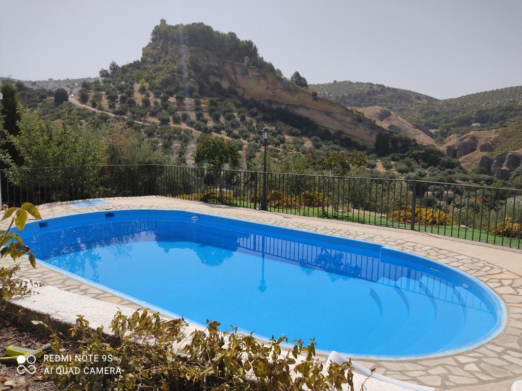 a large blue swimming pool with a mountain in the background at Alojamiento rural El Yate in Montefrío