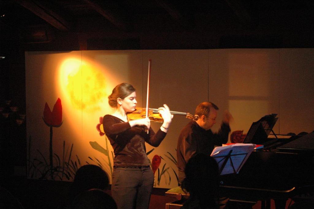 Eine Frau spielt Geige mit einem Mann, der ein Orchester spielt. in der Unterkunft Monegal in San Lorenzo de Morunys