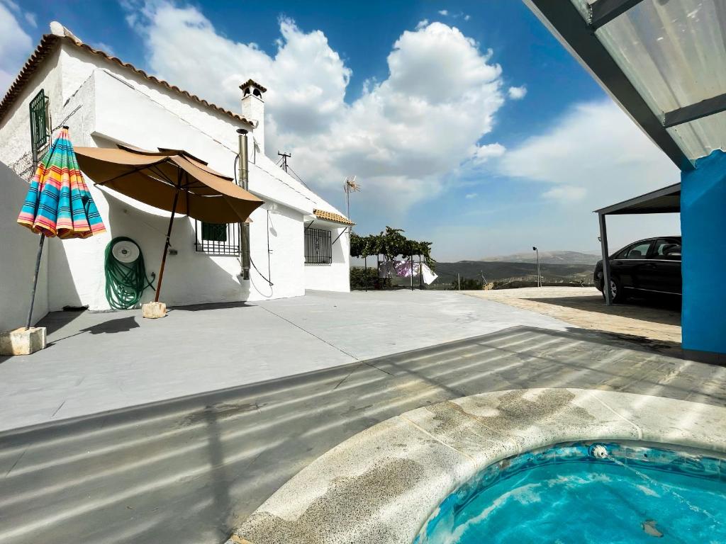 una casa con sombrilla y piscina en Cortijo La Viñolilla en zona rural (Montefrío), en Montefrío