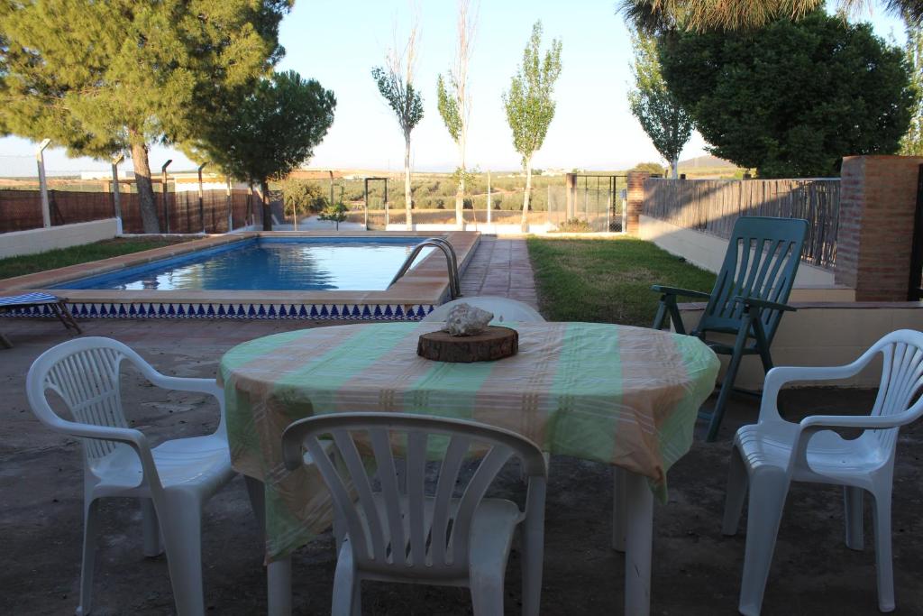 une table et des chaises avec une table et une piscine dans l'établissement Casa Rural La Rosa de los Vientos, à Fuente de Piedra