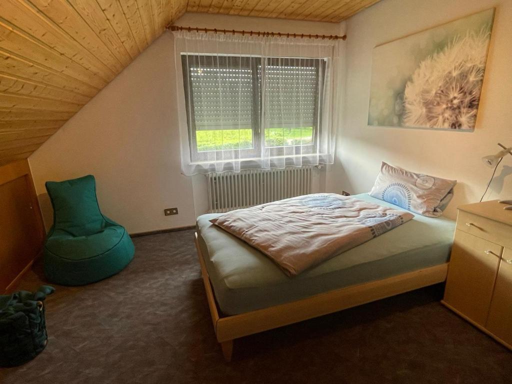 a bedroom with a bed and a green chair at Ferienwohnung Reblandblick in Baden-Baden