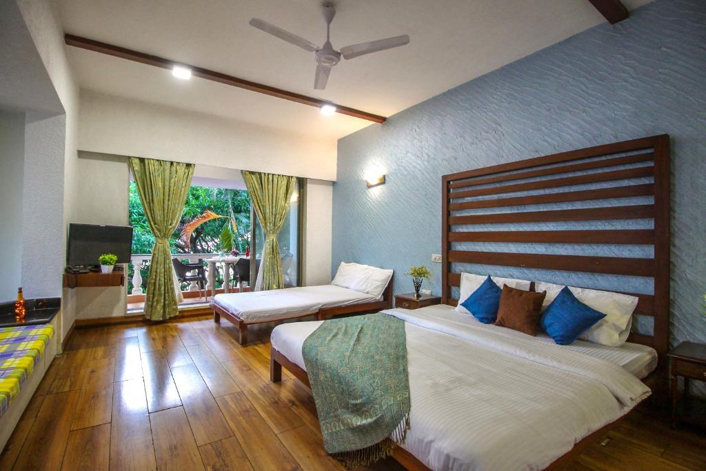 a bedroom with two beds and a large window at EKO STAY - Tropical Beach Apartments in Mumbai