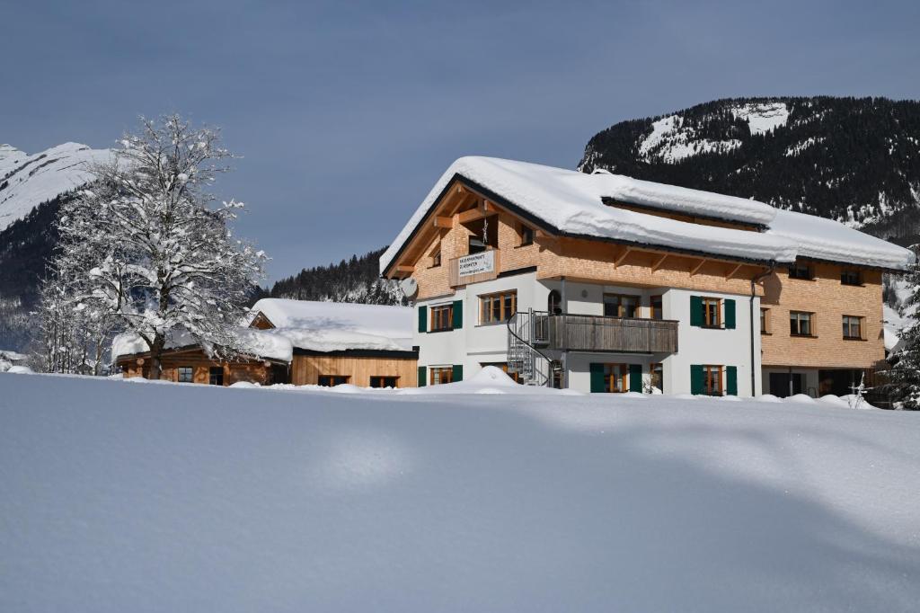 un edificio cubierto de nieve con un montón de nieve en Haus Bergquell, en Au im Bregenzerwald