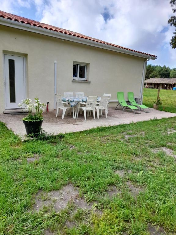 a patio with a table and chairs in front of a house at Maison petit ion jean mi et flo in Vendays-Montalivet