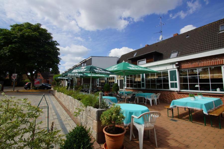ein Restaurant mit blauen Tischen und grünen Sonnenschirmen in der Unterkunft Hotel Grüner Jäger in Travemünde
