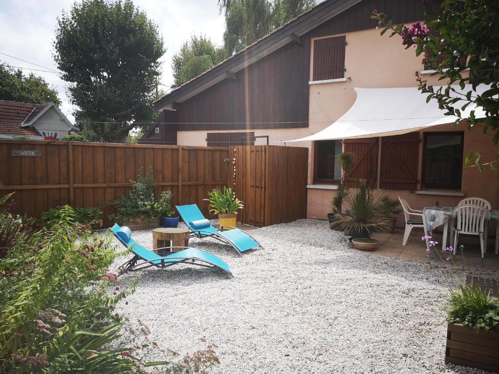een achtertuin met stoelen, een tafel en een hek bij Maison océane proche plage in Arès