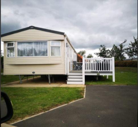 a tiny house with a porch and a white railing at Tattershall Lakes Family Holiday Hot Tub break in Tattershall