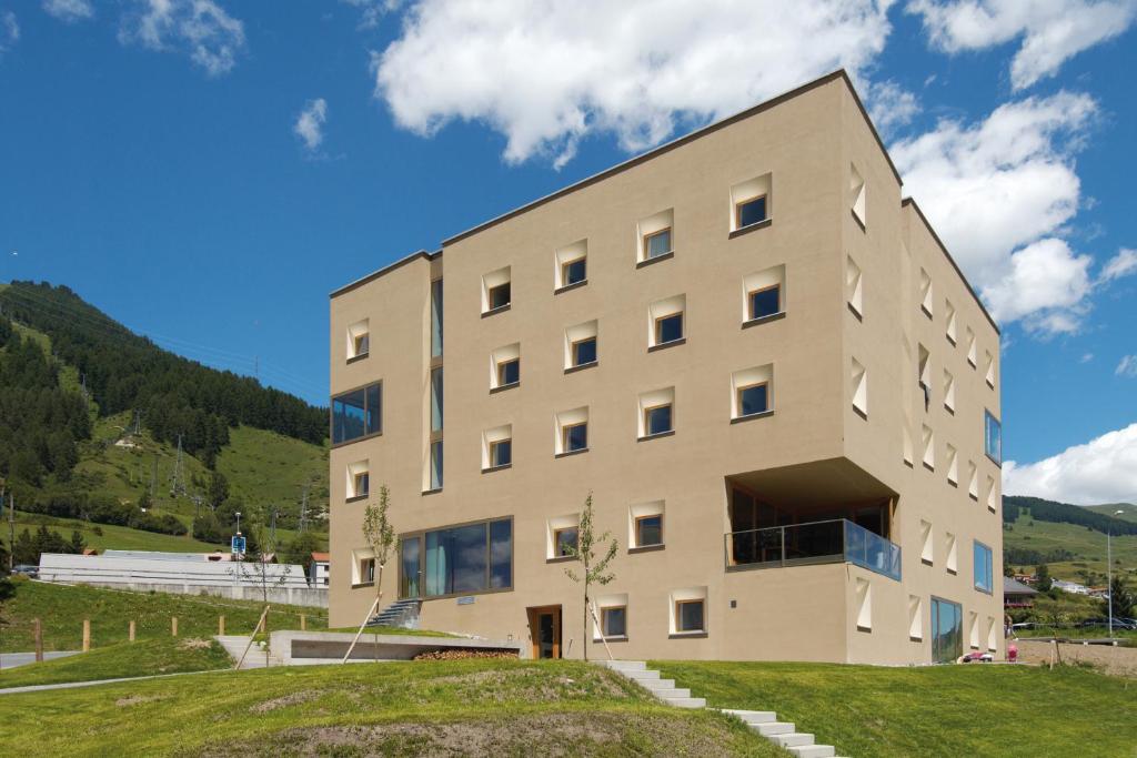 un edificio en la cima de una colina con césped en Scuol Youth Hostel, en Scuol