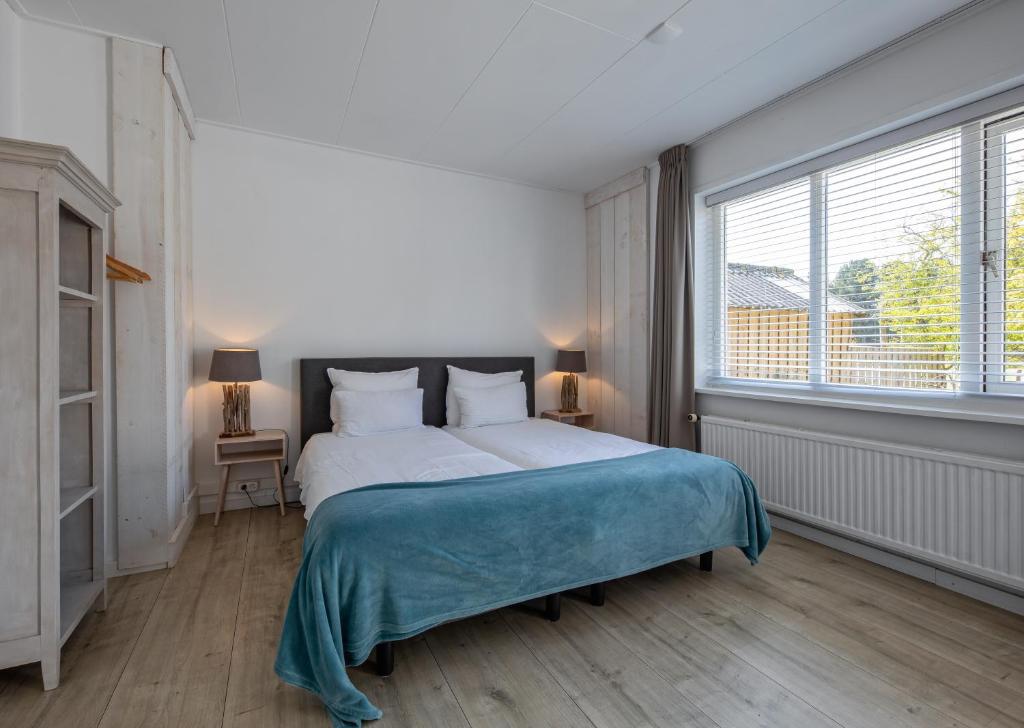 sypialnia z dużym łóżkiem i dużym oknem w obiekcie Zilt Texel w mieście De Cocksdorp