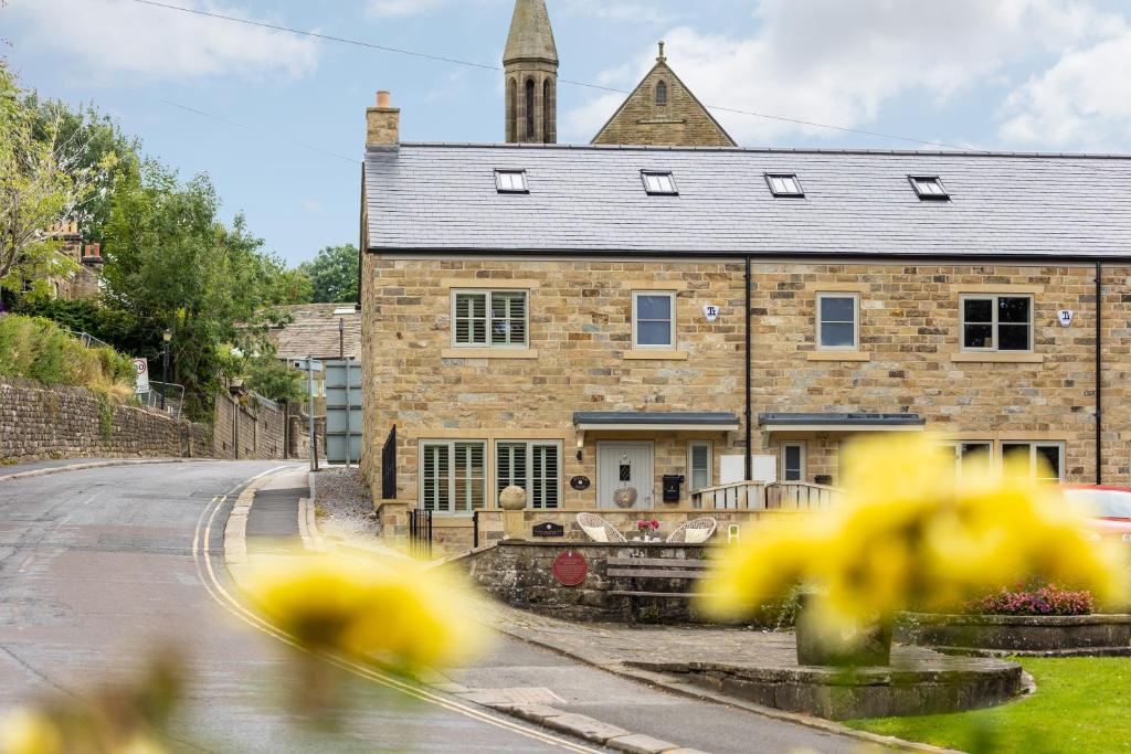 an old brick house with yellow flowers in front of it at Hilltop Snug cosy family home in bustling town of Pateley Bridge in the Yorkshire Dales - Book the combination of rooms and bathrooms you need 1-4 Bedrooms, 2 Bathrooms in Pateley Bridge