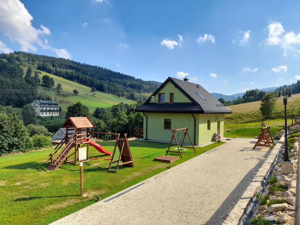 een klein huis met een speeltuin in een veld bij Górskie Zacisze Kamienica in Stronie Śląskie