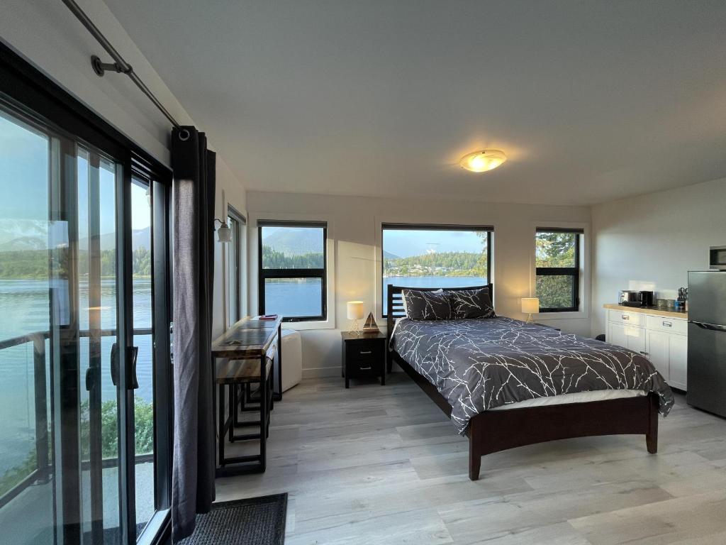 um quarto com uma cama e uma cozinha com janelas em Private Oceanfront Room With Hot Tub Firepit - Shore Thing em Ucluelet