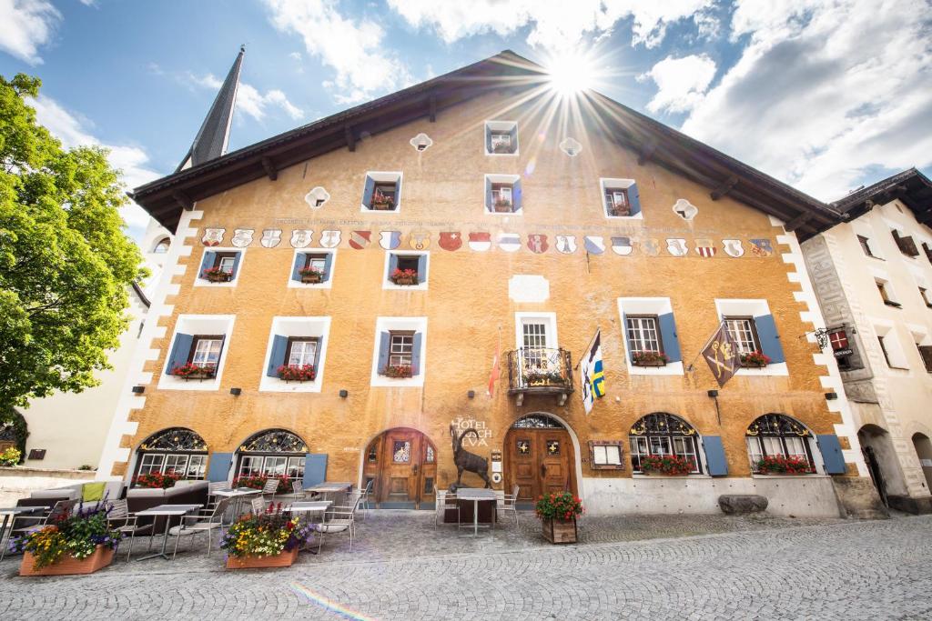 a large brick building with the sun shining on it at Historic Hotel Crusch Alva in Zuoz