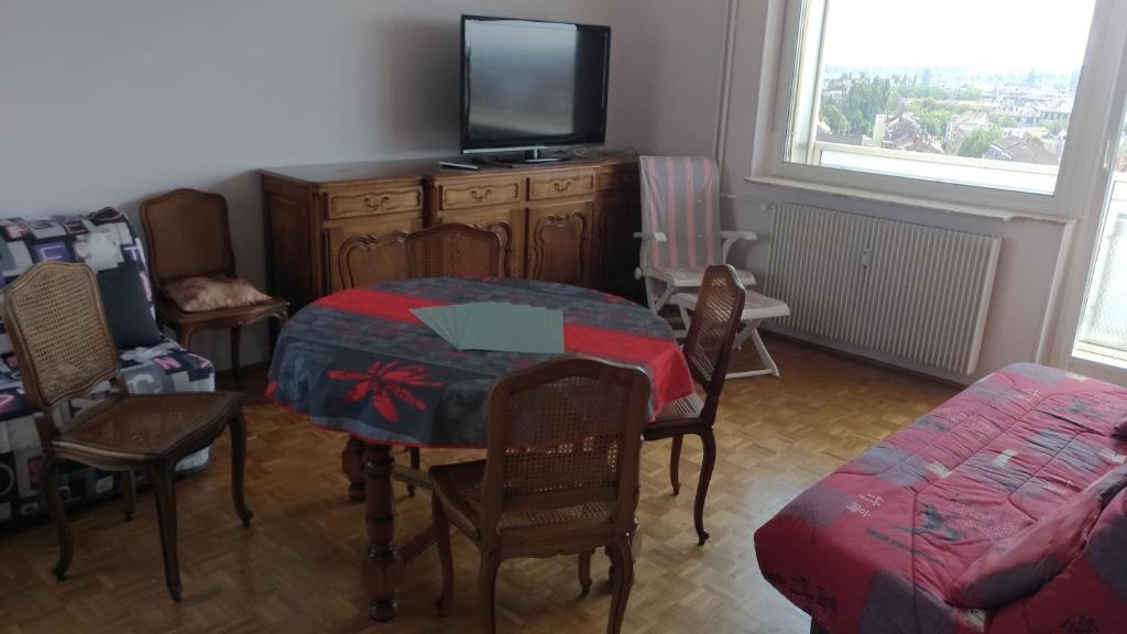 a living room with a dining room table and a tv at La casa du musée in Mulhouse