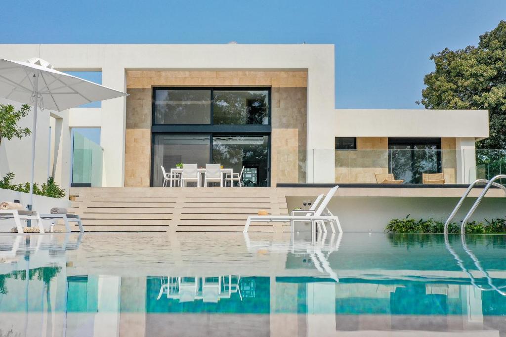 a house with a swimming pool with chairs and an umbrella at Aurum Villas in Ialysos