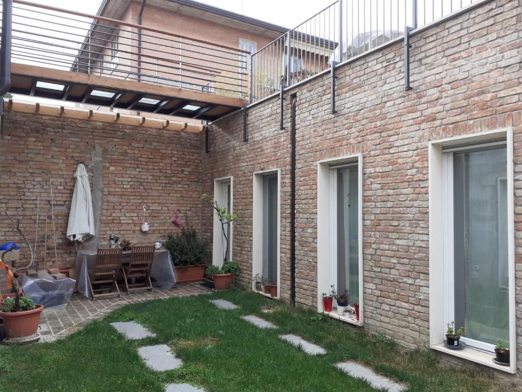 une terrasse avec un mur en briques, une table et des chaises dans l'établissement La Giuggiola, à Padoue