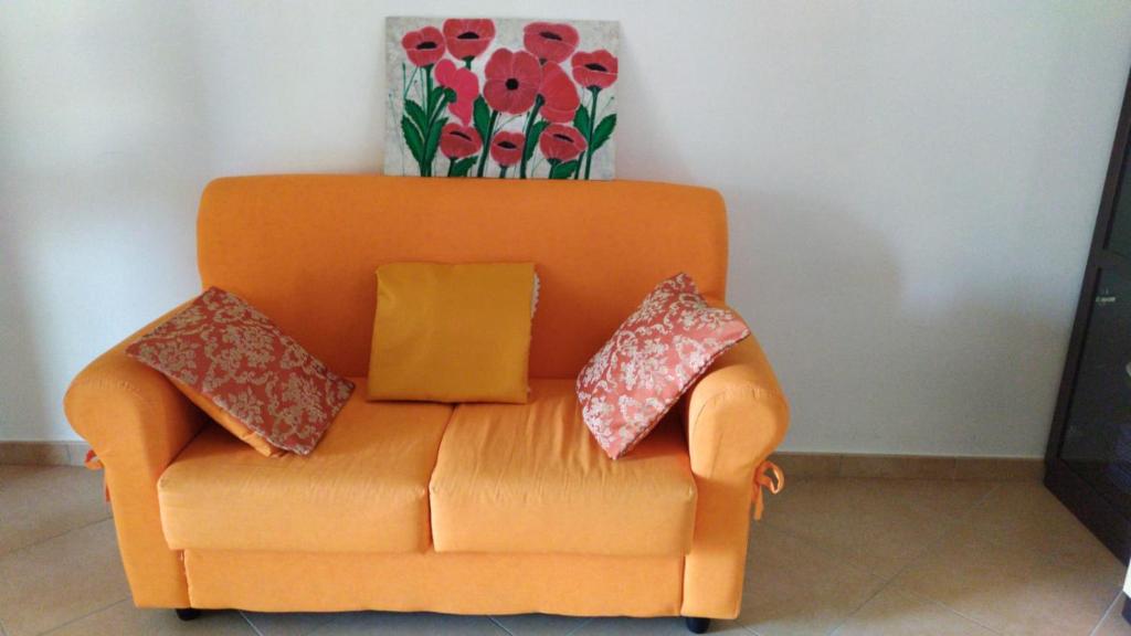 an orange couch with pillows and a vase on top of it at Casa Vacanza Libone in Nova Siri Marina