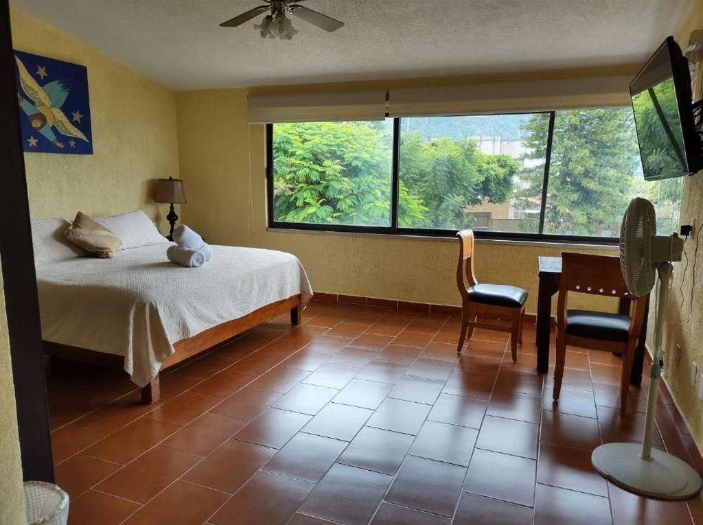 a bedroom with a bed and a desk and a window at Hotel Quinta del Sol in Tepoztlán