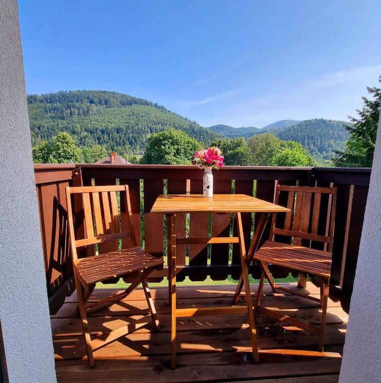 a table with two chairs and a vase of flowers on a balcony at Apartamenty Kolorowa in Szczyrk