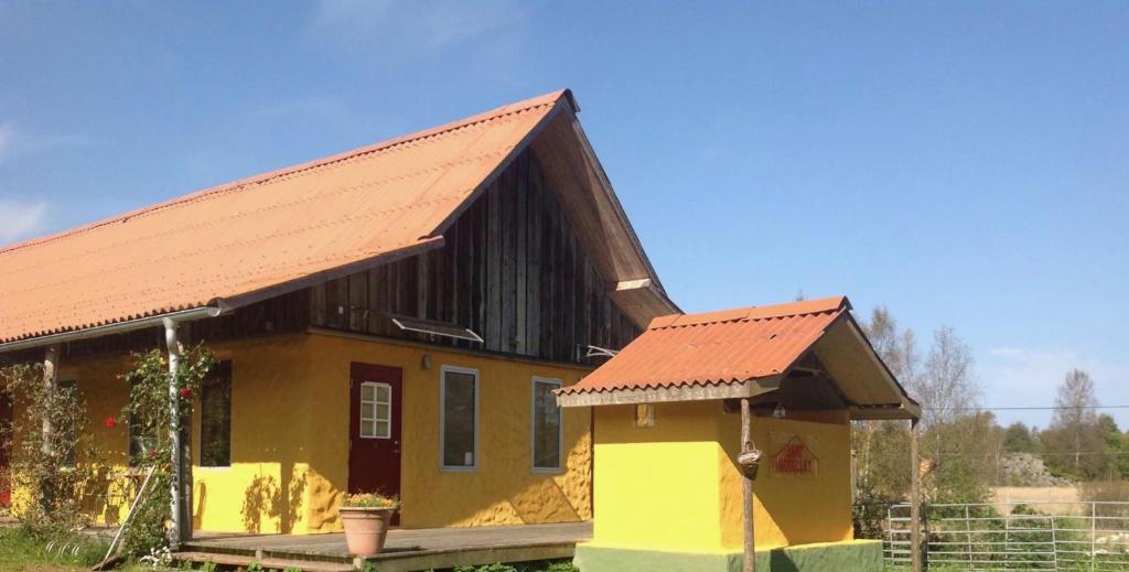 una pequeña casa amarilla con techo naranja en Lanthotellet Hishult en Hishult
