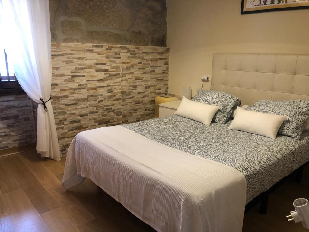 1 dormitorio con cama con almohadas y pared de ladrillo en Casita rural acogedora, en Combarro