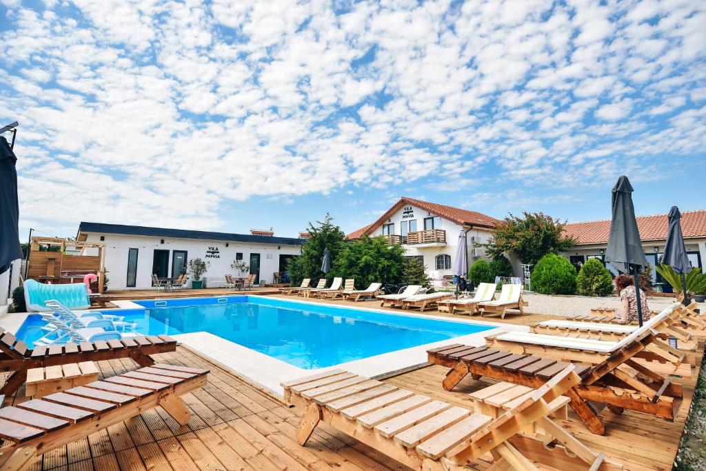 ein Pool mit Chaiselongue und ein Resort in der Unterkunft Vila Medusa in Vama Veche