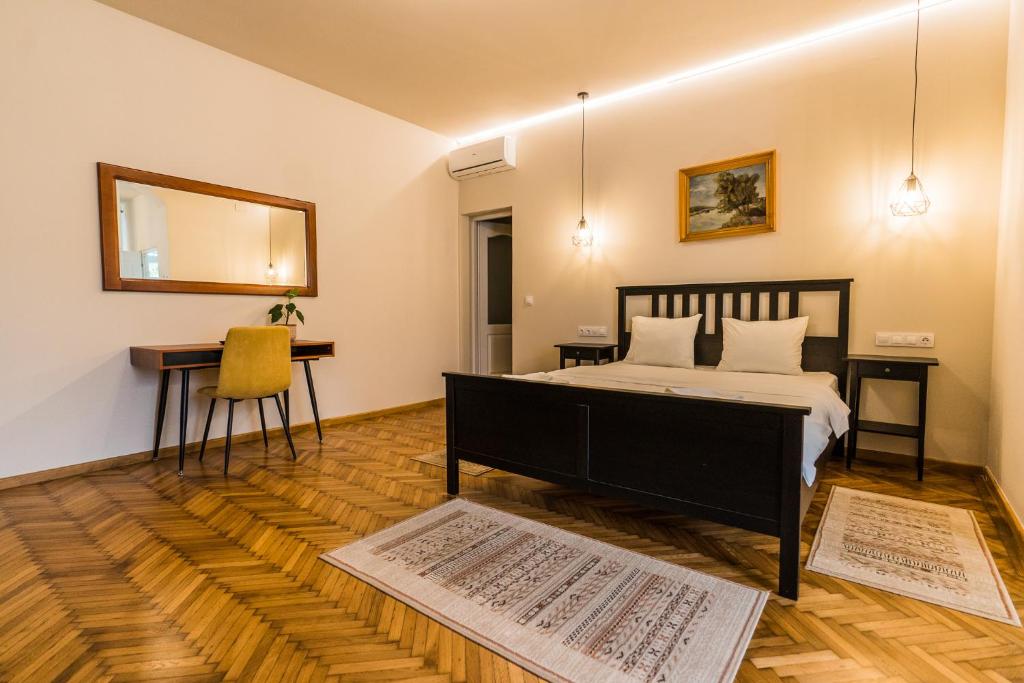 een slaapkamer met een bed, een bureau en een spiegel bij Boutique Rooms with Parking in Oradea