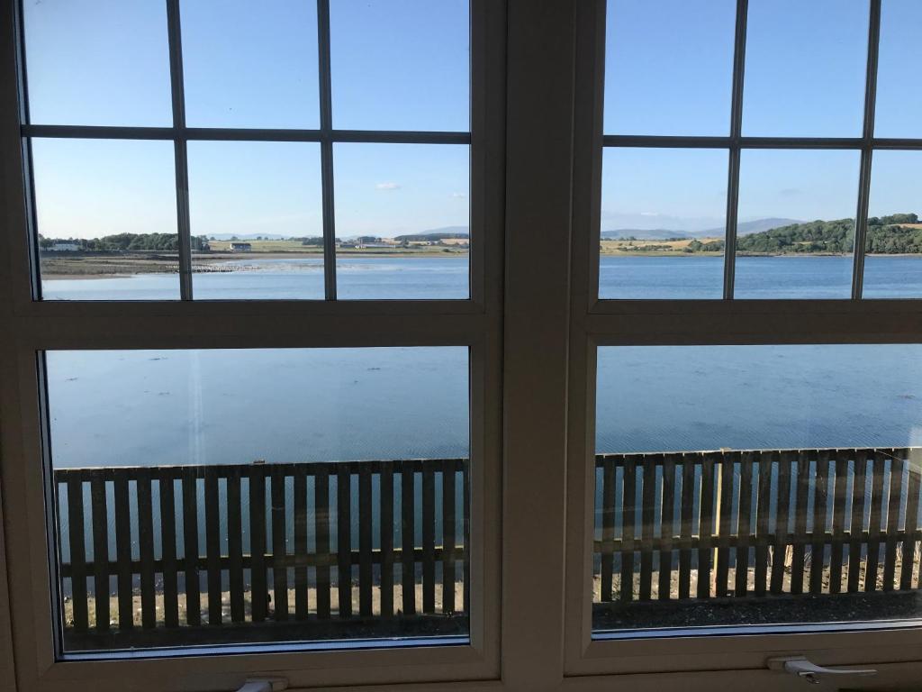 a window with a view of the water seen through it at Harbourside in Garlieston