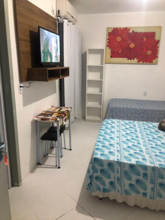 a room with a bed and a desk and a television at Pousada sol in Torres