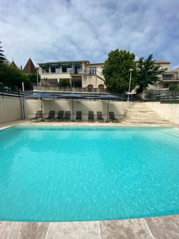 - une piscine d'eau bleue en face d'une maison dans l'établissement Appart’hôtel les perles du lac, à Tombeboeuf