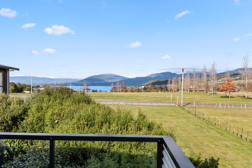 a view of a field with mountains in the background at Lake View Hideaway - Kuratau Holiday Home in Kuratau