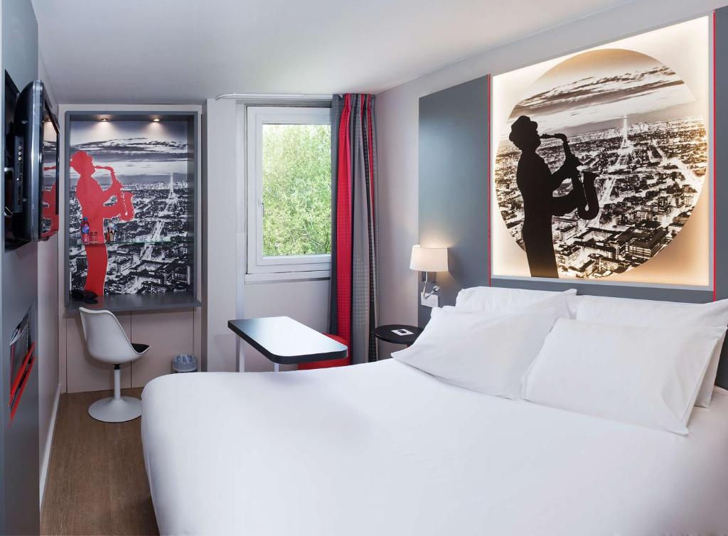 een slaapkamer met een groot wit bed en een raam bij Best Western Paris Saint Quentin in Montigny-le-Bretonneux