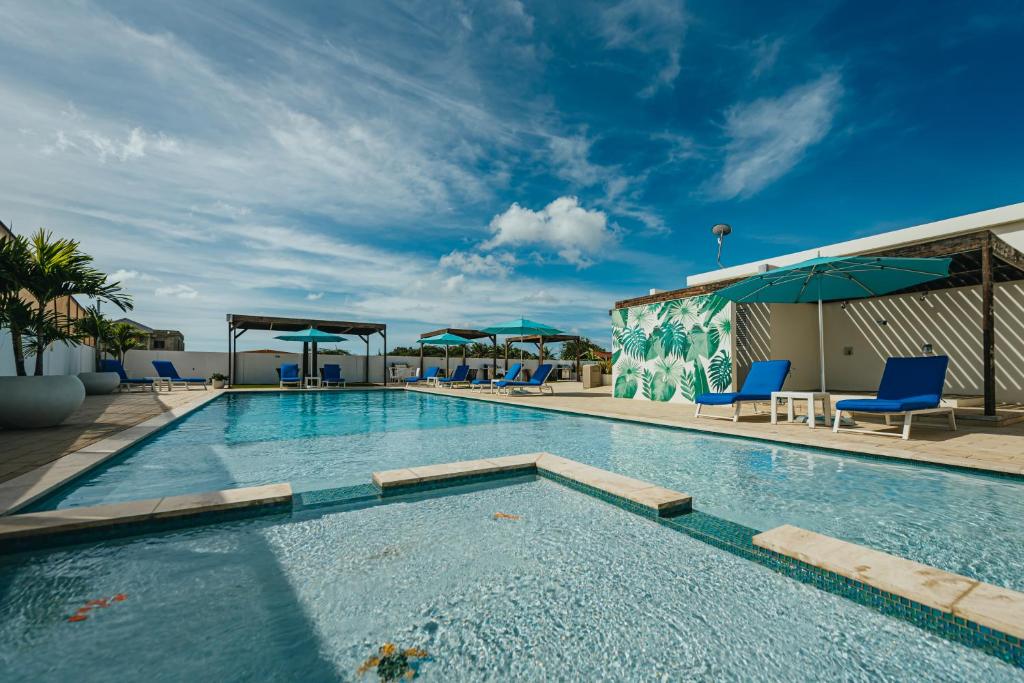 una gran piscina con sillas y sombrillas azules en Lux Villa's by GG en Palm-Eagle Beach