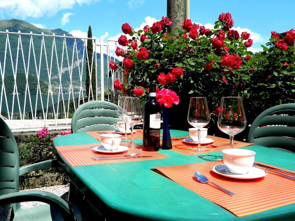 a green table with wine glasses and red flowers at Casa Anto in Lezzeno