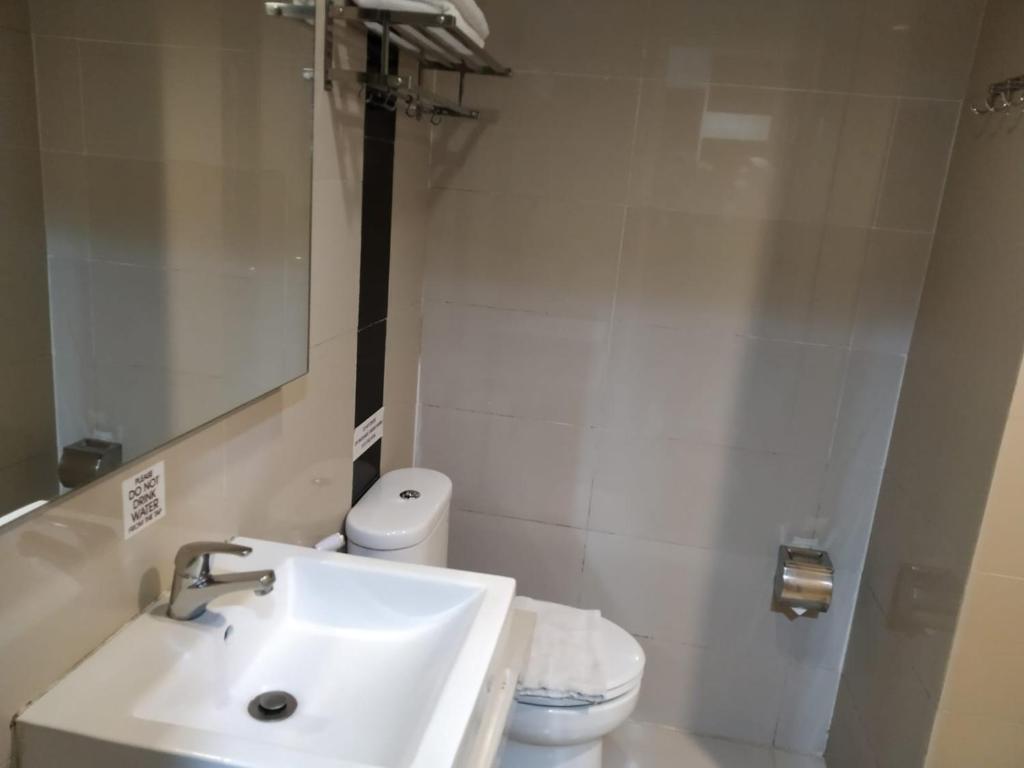 La salle de bains blanche est pourvue d'un lavabo et de toilettes. dans l'établissement Batusuki Resort & Hotel, à Batu