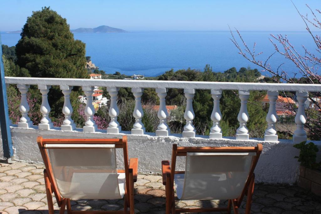 two chairs sitting on a balcony looking out at the ocean at Votsalo Apartments in Patitiri