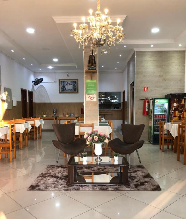 a dining room with a chandelier and a table and chairs at Hotel Mirante do Porto in Aparecida