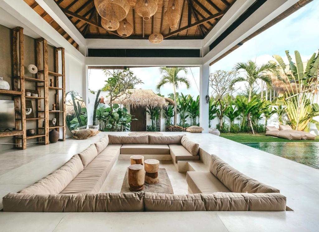 a living room with a large couch in front of a pool at MODJO Villas Bingin in Uluwatu