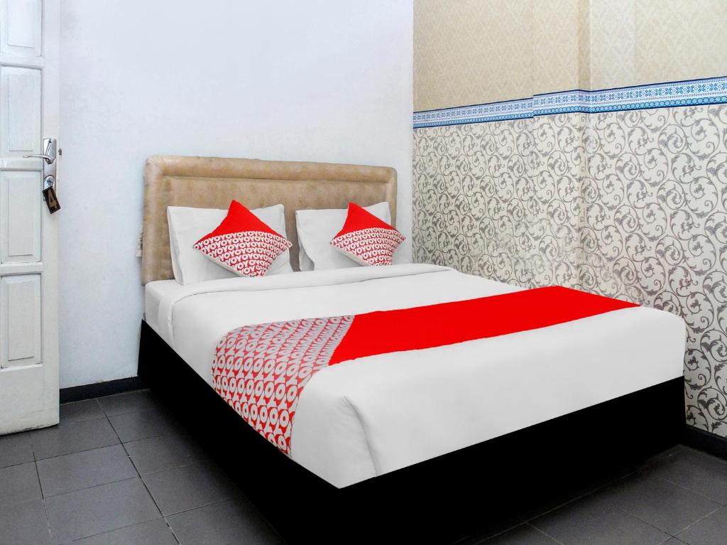 a bedroom with a bed with red pillows at SPOT ON 2353 Wisma Hulubalang in Palembang