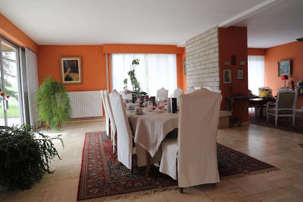 uma sala de jantar com uma mesa com cadeiras brancas em B&B La Maison de L'Aubette em Magny-en-Vexin