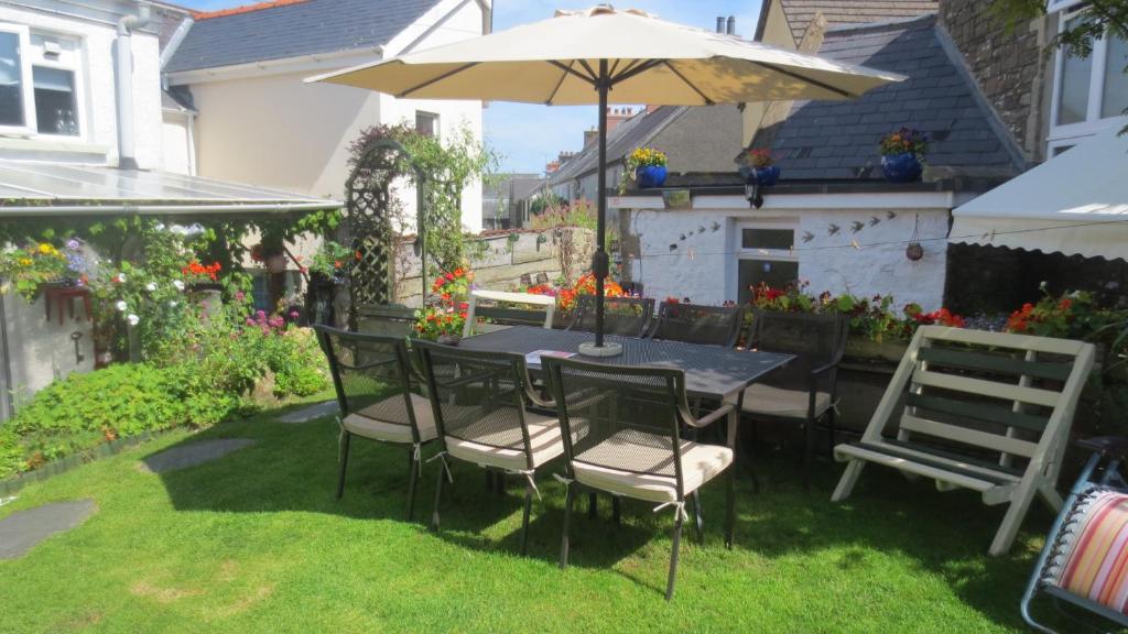 a table and chairs with an umbrella in a yard at Hamilton Lodge - Cottage sleeps 8 in Fishguard