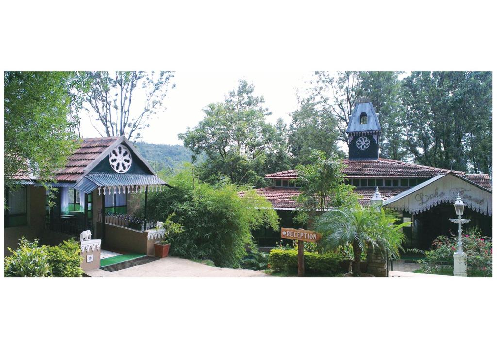 ein Gebäude mit einem Uhrturm darüber in der Unterkunft INDeco Lake Forest in Yercaud