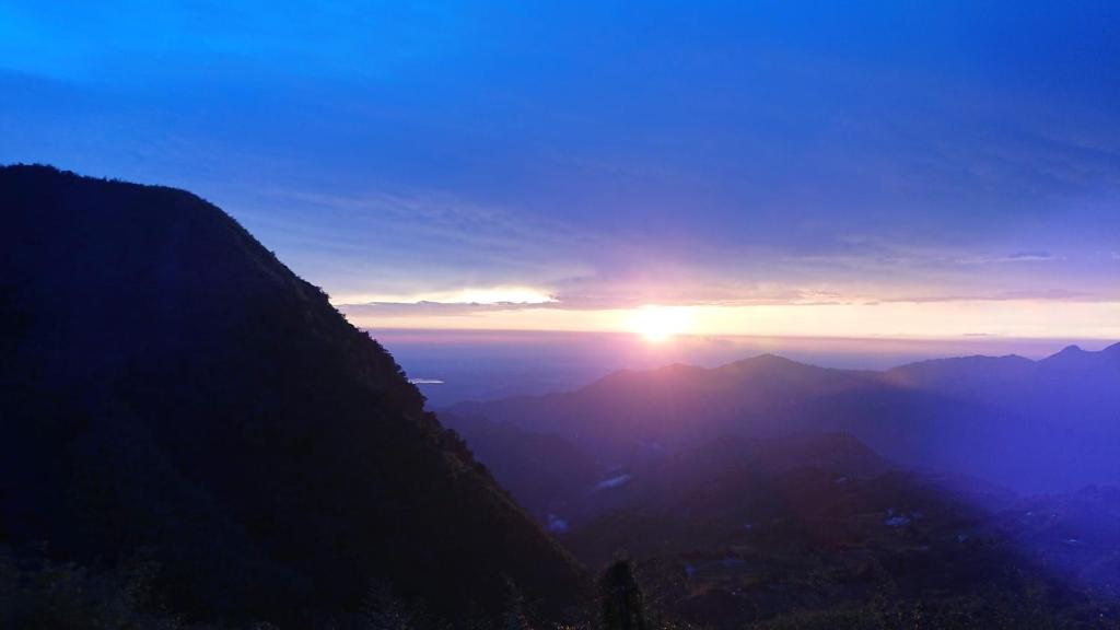 a view of the sun setting over the mountains at 阿里山梅園樓觀景飯店 in Fenqihu