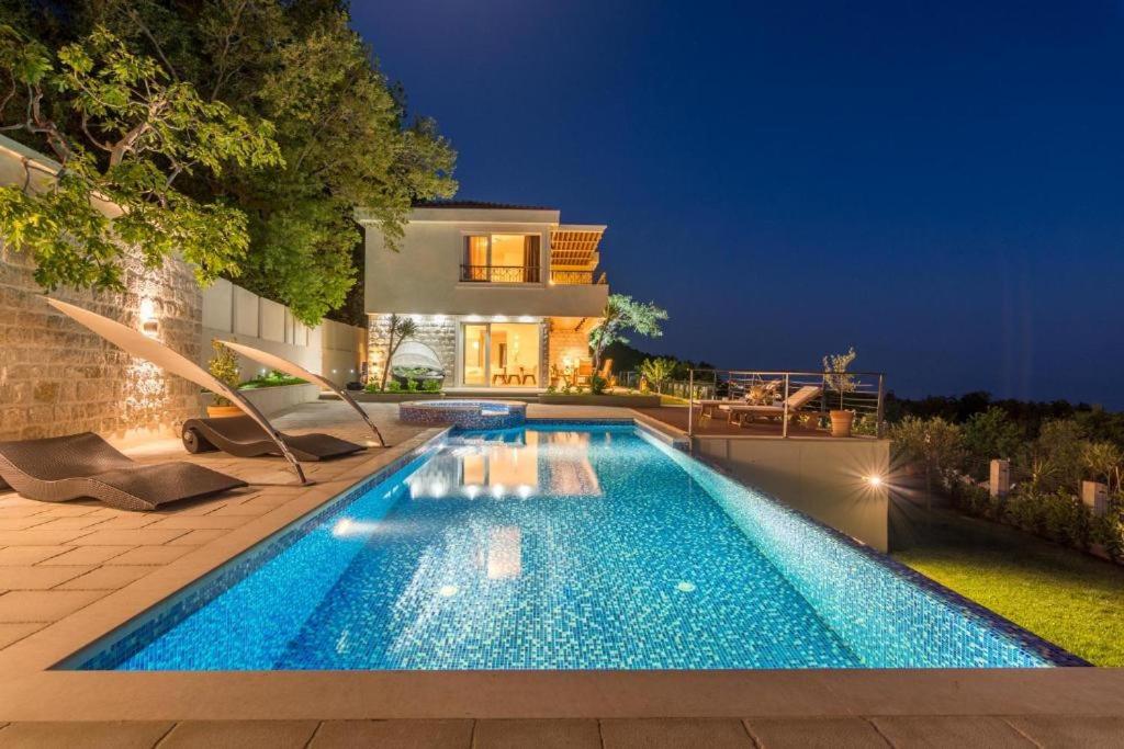 una piscina frente a una casa por la noche en Luxury Villa Crystal Blue, en Sveti Stefan